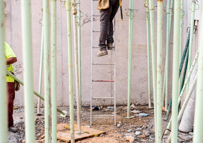 Man climbing a ladder on a building site with no support