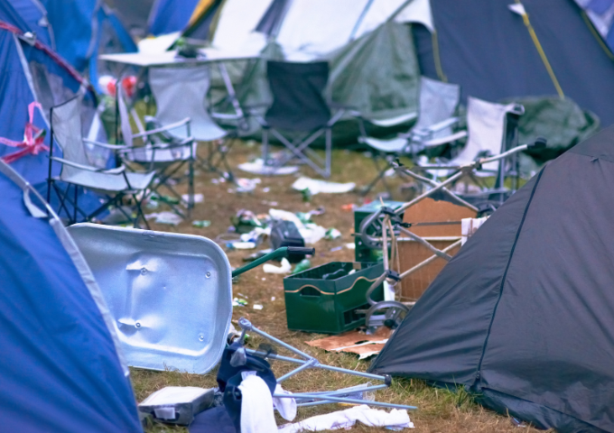 A photo of mess at a campsite - tents and rubbish are left are strewn on the floor.