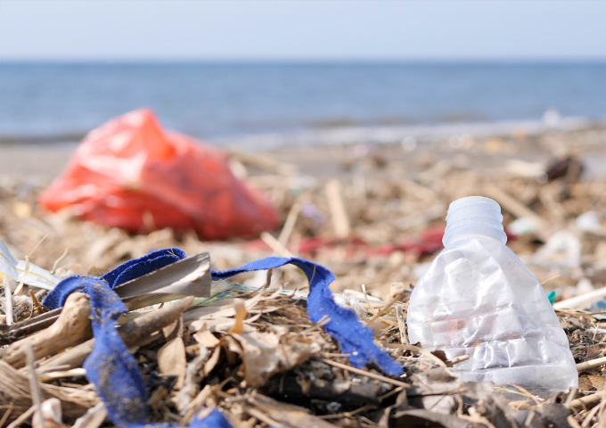 A photo of a plastic bottle and other rubbish on a beach